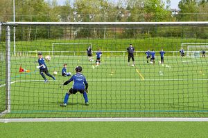Kinder-Fußballtraining mit Trainer, Blick von hinter dem Tornetz