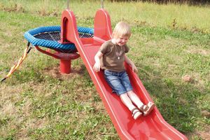 Kinder auf Spielplatzgerät Spatzennest mit Rutsche