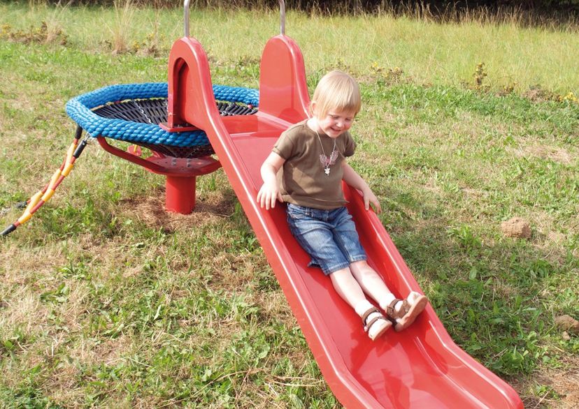 Kinder auf Spielplatzgerät Spatzennest mit Rutsche